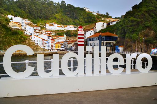 A fantastic shot of a port with the sign of Cudillero in Asturia Spain and colorful houses in a green valley in the background