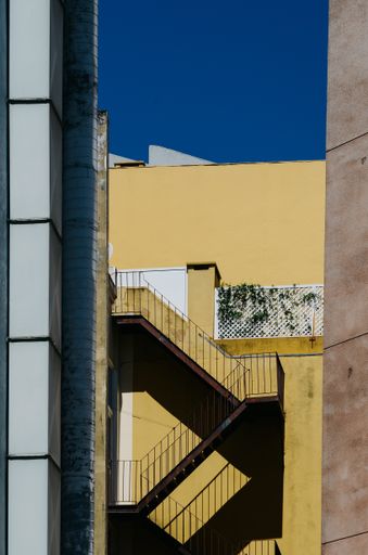 A vertical shot of a tall yellow building with stairs in Portugal