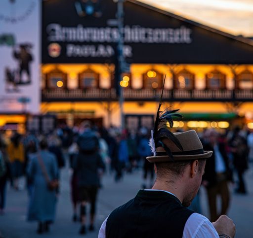 close up shot of visitor at Munich Oktoberfest with other people and beer tent in blurred background.