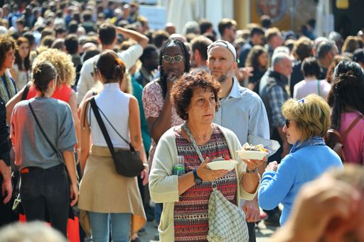 A woman walking in a crowded area while holding Italian street food in her hands