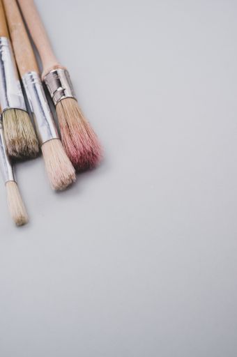 A vertical closeup focus shot of paintbrushes on a gray surface