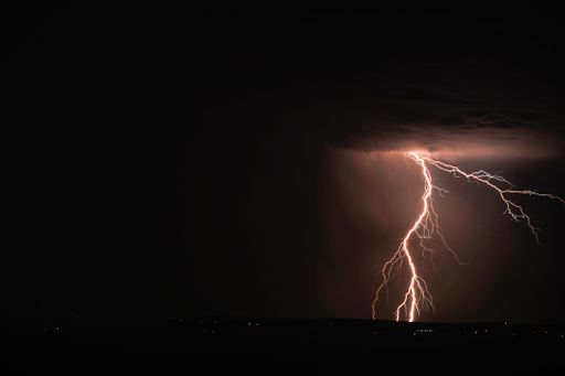 A lightning and storm clouds over the sea and the city.