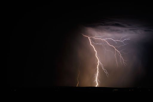 A lightning and storm clouds over the sea and the city.