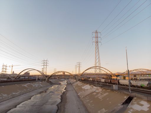 A Drone flying at sunset in the Los Angeles River over the 6th Street Bridge