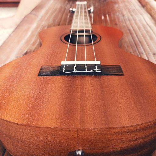 A closeup shot of details on a brown acoustic guitar on the floor
