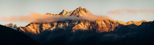 A scenic panoramic shot of the Dolomites in Italy during sunset with clouds covering the summit
