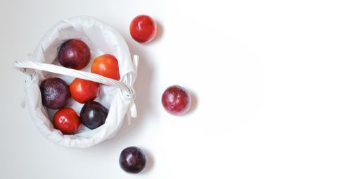 A top view of plums in a small basket isolated on a white background