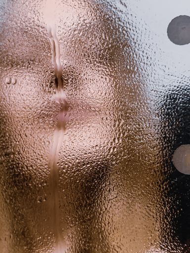 Vertical shot of a person with her phone on the wet mirror