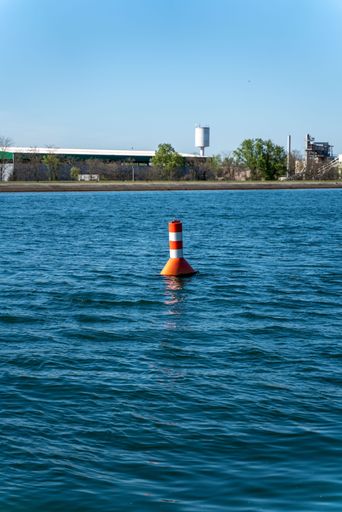 A vertical shot of a buoy floating on the surface of a lake in the countryside