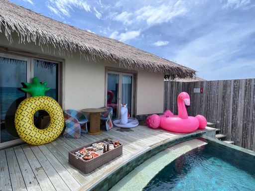 The view of a served breakfast and swimming tubes by the pool of a resort house