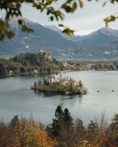 A vertical shot of an old chapel on a green island against mountains at Lake Bled, Slovenia
