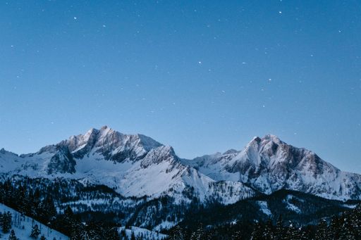 A scenic view of Mountain Sneffels covered with pine forests and snow at starry night in Chicago
