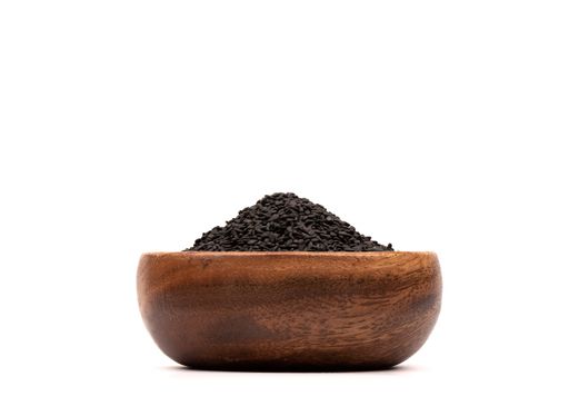 A pile of black sesame seeds in a wooden bowl isolated on white background (Copy space)