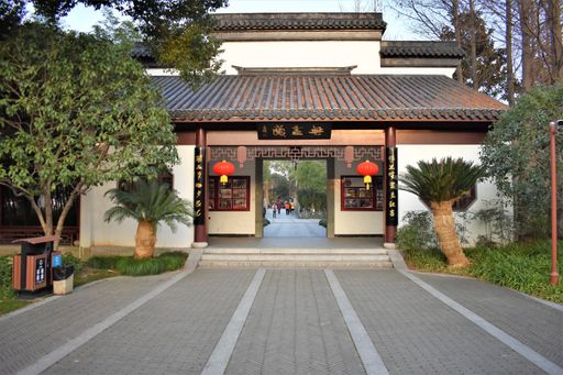A Chinese style alcove near the pond in a public park with people around