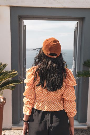 The back of a young woman in front of a door with a view of the sea