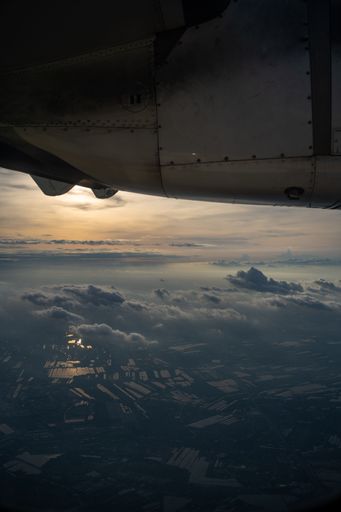 An airplane flying over clouds during sunset