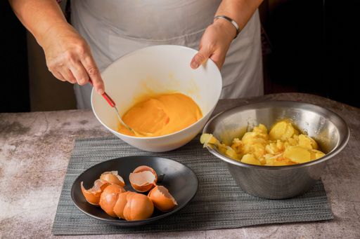 woman in apron beating eggs in a bowl