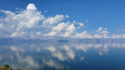 A beautiful shot of a bright blue sky with fluffy clouds over calm water-perfect for wallpapers