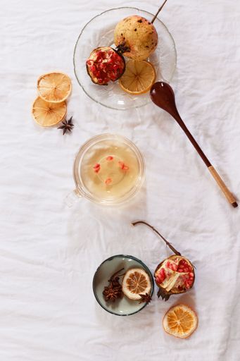 Vertical overhead view of pomegranate fruit and dried lemon slices for juicing, showing an autumn theme aesthetic background