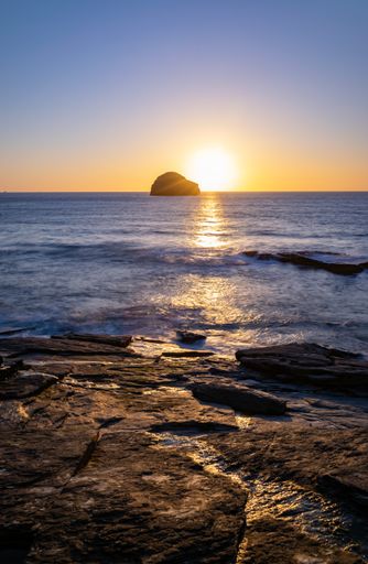 Long exposure of an orange sunset of a rocky English beach at high tide