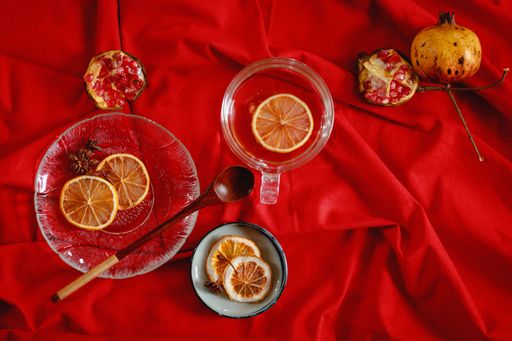 Top view of pomegranate fruits and lemon slices on a red background to make fresh juice that shows wellness and autumn aesthetic