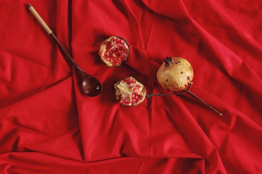 Overhead view of pomegranates on a deep red colored background showing the concept of autumn season