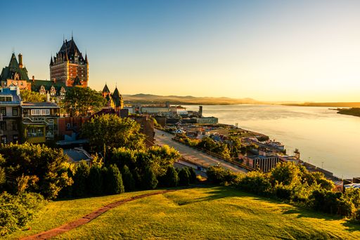 A beautiful view of the Chateau Frontenac surrounded by greenery in Quebec, Canada at sunrise