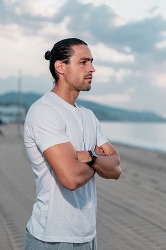 A young athletic Caucasian male working out on the beach in the early morning - healthy lifestyle concept