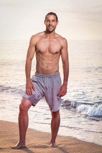 A young athletic Caucasian male working out on the beach in the early morning - healthy lifestyle concept