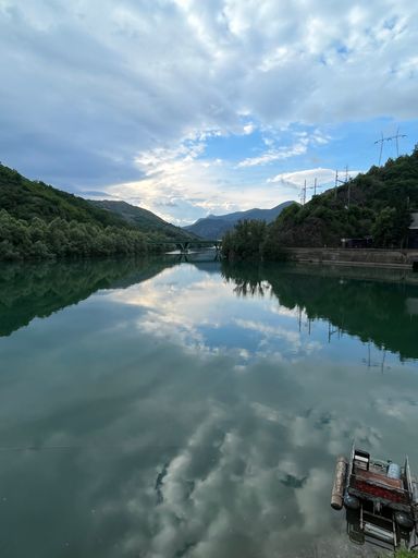 A beautiful landscape of a lake with calm waters that reflect the background of trees and clouds