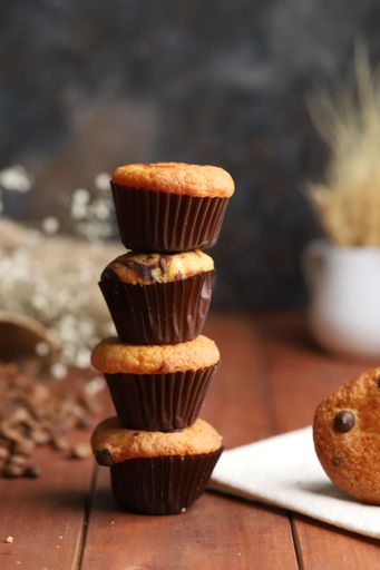 some muffins one over other in a row fresh baked over wood table texture and flowers behind