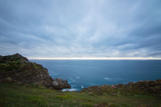 A beautiful scenery of splashing sea waves with rocky cliffs under a cloudy sky