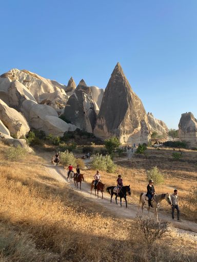 The People on a horse riding tour through a pathway in the rocky hills in Cappadocia