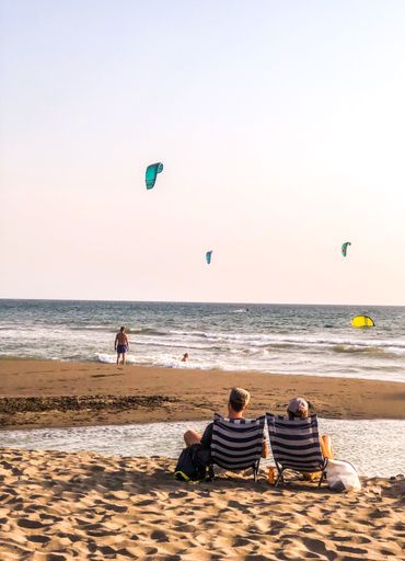 A beautiful vertical shot of people relaxing at the beach at soft sunset