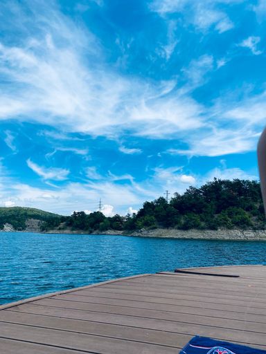 A vertical shot of a wooden pier at a lake with beautiful clouds in the sky
