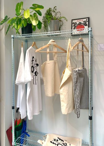 A vertical shot of minimalist and aesthetic clothes and bags hanging on a rack