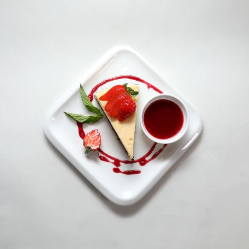 A top view of a piece of cheesecake with a strawberry on a plate isolated on a white background