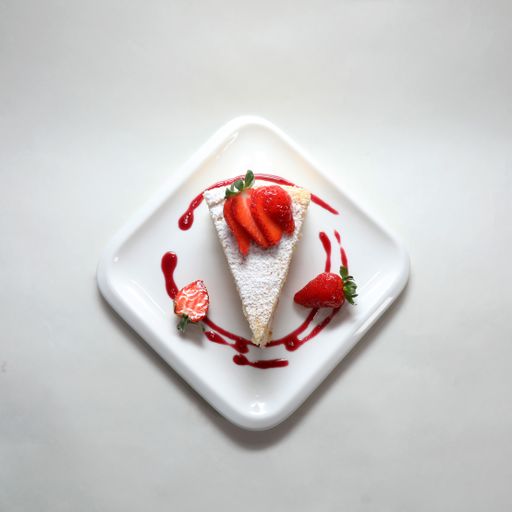 A top view of a piece of cake with strawberries on a plate isolated on a white background