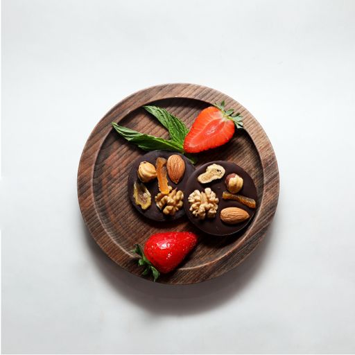 A top view of chocolate medians with nuts and strawberries on wooden board isolated on a white background