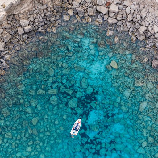 A high angle shot of a single boat in the middle of the ocean surrounded by rock formations