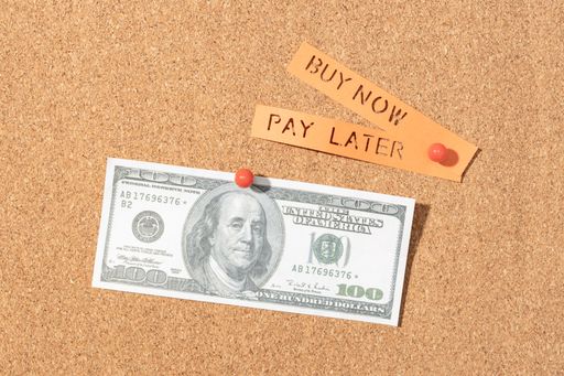 Buy now pay later concept. US dollar banknote and message label pinned on cork board