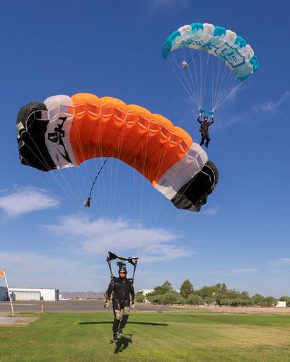 Two skydivers land next to each other on the DZ