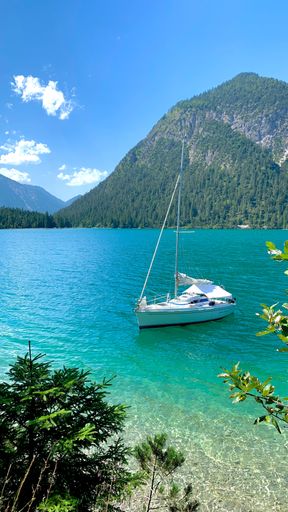 A vertical shot of a white yacht with a background of mountains