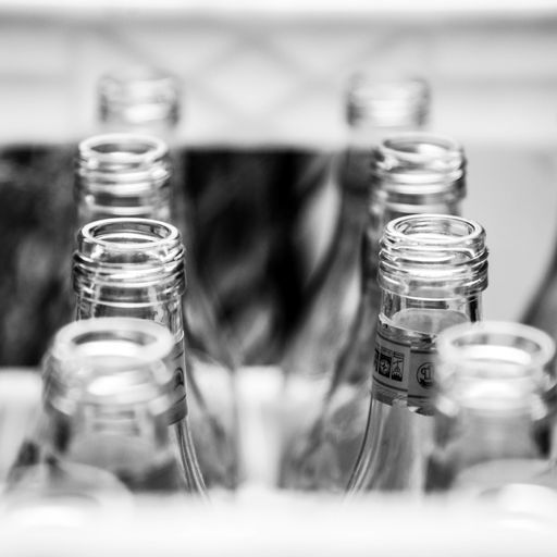 A closeup grayscale shot of empty glass bottles