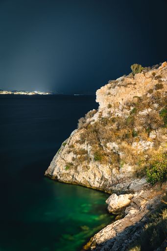 A breathtaking shot of calm sea with turquoise water and rocky coast at night, island in Greece-perfect for wallpaper