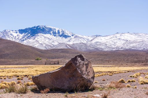 A big stone against the Andes mountains covered in snow in Mendoza, Argentina