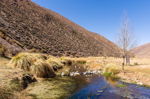 A scenic shot of a field with a stream against the mountains background in Mendoza, Argentina