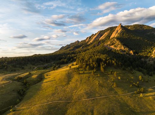 A scenic view of the Flatirons of Boulder, Colorado on a sunny day under a bright cloudy sky
