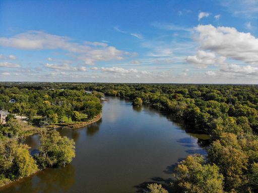 A high angle shot of a river flowing between green trees on a sunny day