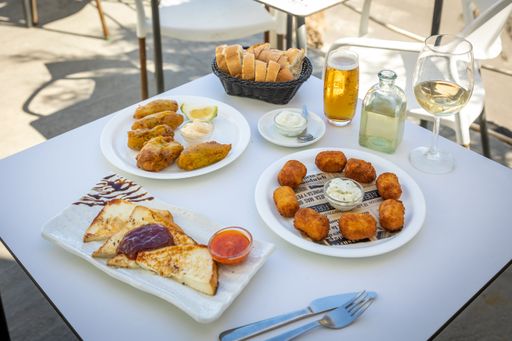 A close-up shot of fried fast food and French toast on a white table in an open-air cafe